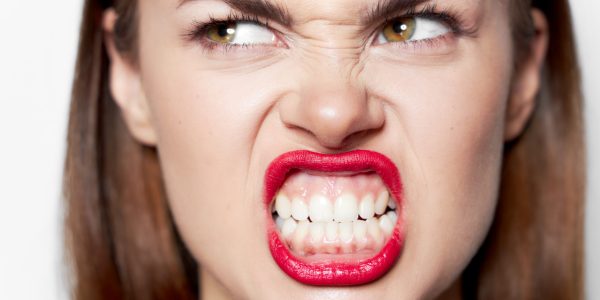 Portrait of a woman bares her teeth and looks aside a grimace of emotion